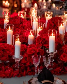 a table topped with lots of red roses and candles