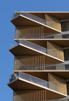 an apartment building with balconies and balconies on the top floor, against a blue sky