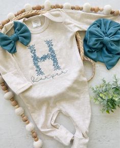 This sweet sleeper is soft and comfortable to snuggle a little one. This features a soft oatmeal romper with a large floral embroidered letter and name in a cute font in the name of your choice, and an option for a matching muted blue bow. This outfit makes a perfect coming home outfit, newborn pictures, or baby shower gift.  This romper has cute little footies that cuff for a newborn, and will uncuff to add length as baby grows. It has fold over mittens for tiny hands. It has snaps around legs Newborn Embroidery Clothes, Outfit Baby Shower, Newborn Coming Home Outfit, Baby Girl Outfit, Tiny Hands, Going Home Outfit, Cute Fonts, Muted Blue, Floral Letters