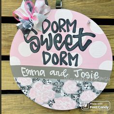 a sign that says dorm sweet dorm hanging on the side of a wooden fence with flowers