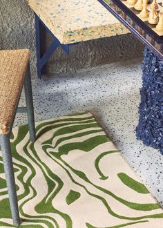 a table with chess pieces on it in front of a rug and chair next to the table