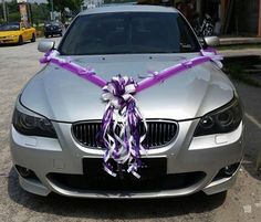 a silver car with a purple ribbon tied to it