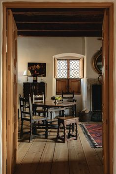 an open door leading to a dining room with wooden floors and walls, along with a fireplace