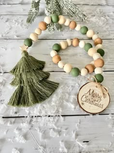 a christmas tree ornament and wooden bead necklace on a white wood background