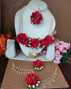 the necklace and earrings are decorated with red flowers, pearls, and pearls on display