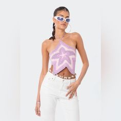 a woman wearing white pants and a purple crop top with an intricate star design on it