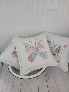 two pillows with butterflies on them sitting on a table