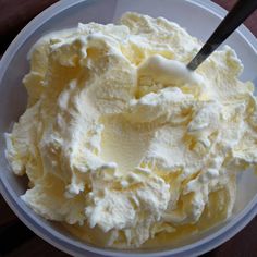 a white bowl filled with whipped cream on top of a wooden table