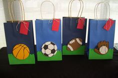 three bags decorated with sports related items are on a black cloth covered table in front of a window