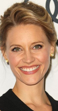 a woman with blonde hair smiling at the camera and wearing gold earrings on her head