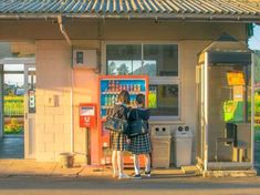 two people standing in front of a kiosk on the side of a road