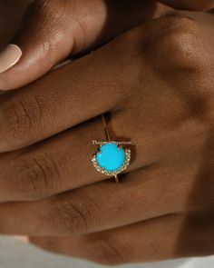 a woman's hand holding a ring with a turquoise stone in it and diamond accents