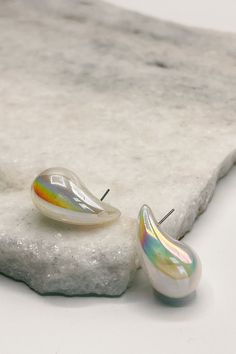 The Kelly Iridescent Scoop Studs are a captivating fusion of modern design and ethereal beauty, crafted to enchant with their iridescent shimmer. These stud earrings feature teardrop-shaped gems that exhibit a mesmerizing play of colors, reminiscent of the shifting hues seen in a soap bubble or the gleam of a seashell in sunlight. At the heart of each earring is a carefully selected iridescent gem, known for its ability to reflect and refract light in a myriad of colors. The smooth, polished sur White Drop Teardrop Earrings For Party, White Teardrop Earrings For Party, Clear Teardrop Earrings, Soap Bubbles, Best Birthday Gifts, Ethereal Beauty, Classic Man, Unisex Style, Mens Shirt Dress