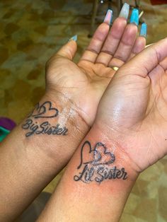 two people with matching tattoos on their arms holding each other's hands in the air