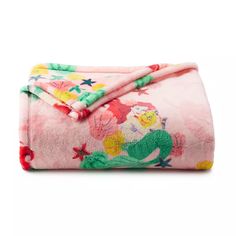 a pink blanket with flowers and mermaids is folded up on a white surface in front of a white background