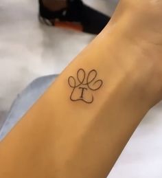 a dog paw tattoo on the wrist is shown in black ink and has a small bow at the center