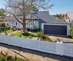 a house with a white fence in front of it and a tree on the other side