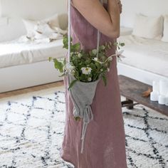 a woman in a pink dress holding a bouquet of white flowers and greenery on her back