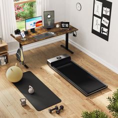 there is a desk with a laptop and exercise mats on the floor next to it