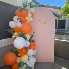 an orange and white balloon arch on the side of a building