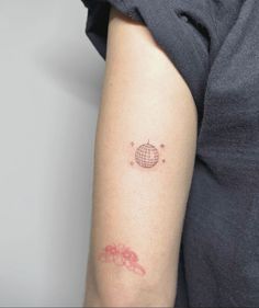 a woman's arm with a small globe tattoo on the left side of her arm