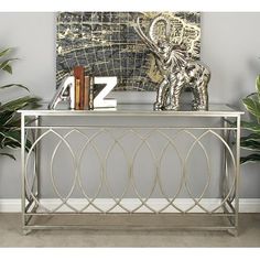 a metal console table with books on top and a painting in the corner behind it