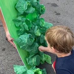 a little boy that is standing in front of a box with some leaves on it