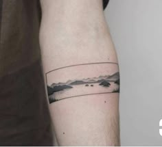 a man's arm with a small landscape tattoo on the left side of his arm