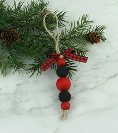 a christmas ornament hanging from a pine tree with red and black balls on it