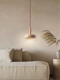 a living room with a couch, table and lamp hanging from the ceiling over it