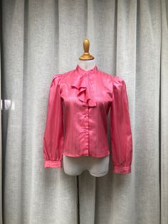 "For sale is a vintage 80s victorian style pink  polyester blouse by Liberation with shiny silver stripes, button down with pink faux pearl buttons and padded shoulders. Buttoned up to a high neck with jabot ruches. Marked size M.  Measurements (flat): Sleeve length: 23\" Shoulder to shoulder: 15\" Armpit to armpit: 18\" Shoulder to hem: 22\"" Fitted Retro Pink Blouse, Pink Feminine Blouse For Formal Occasions, Feminine Pink Formal Blouse, Pink Formal Blouse For Fall, Formal Pink Blouse For Fall, Vintage Pink Puff Sleeve Top, Pink Formal Blouse For Spring, Fitted Vintage Pink Blouse, Vintage Pink Tops For Party