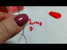 someone is doing something with red thread on the table cloth and they are making letters