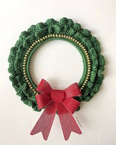 a green wreath with a red bow hanging on the wall