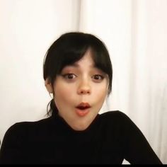 a woman making a funny face while wearing a black shirt and posing for the camera