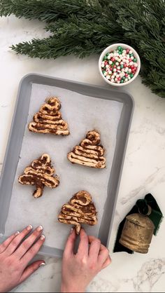 someone making christmas cookies on a baking sheet