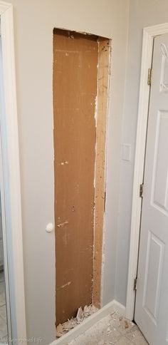 an unfinished wall in the corner of a room with a door and window frame missing