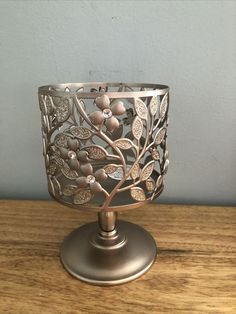 a metal candle holder sitting on top of a wooden table