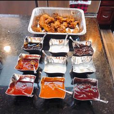 many different types of sauces and condiments in trays on a counter