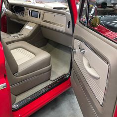 the interior of a red car with beige leather seats and floor mats on display in a showroom