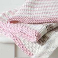 a pink and white blanket sitting on top of a bed