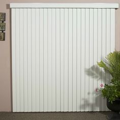 a potted plant sitting in front of a sliding door with vertical slats on it