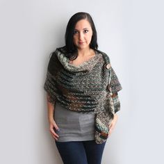 a woman standing in front of a white wall wearing a knitted shawl and leggings