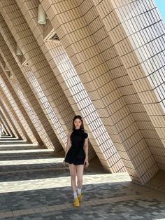 a woman is standing in front of a wall with many lines on it and wearing yellow boots