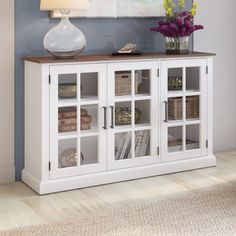 a white bookcase with glass doors on the front and bottom, in a living room