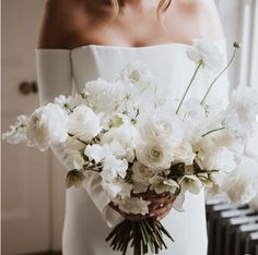 a woman holding a bouquet of white flowers