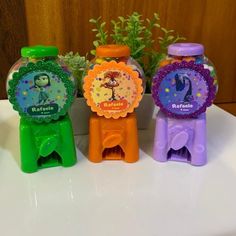 three plastic watches sitting next to each other on a white surface with plants in the background