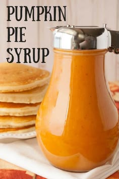 pumpkin pie syrup in a glass carafe next to stack of pancakes