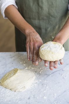 a person is kneading dough into a ball on a counter top with one hand