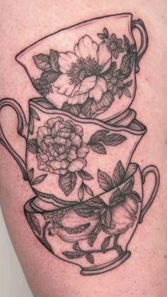 a black and white tattoo of two tea cups with flowers on the inside of them