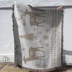 a blanket hanging on the side of a building with deers and snowflakes